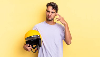 İspanyol yakışıklı adam kafası karışık ve şaşkın hissediyor, senin deli olduğunu gösteriyor. Motosiklet kaskı konsepti