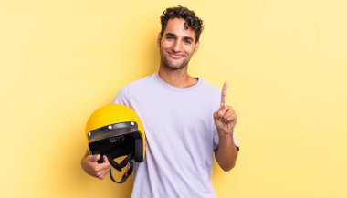 İspanyol yakışıklı adam gülümsüyor ve arkadaş canlısı görünüyor, bir numarayı gösteriyor. Motosiklet kaskı konsepti