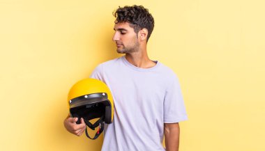 Profil görünümlü İspanyol yakışıklı adam hayal mi kuruyor, hayal mi kuruyor, hayal mi kuruyor? Motosiklet kaskı konsepti