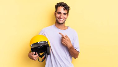 İspanyol yakışıklı adam neşeyle gülümsüyor, mutlu hissediyor ve bir tarafı işaret ediyor. Motosiklet kaskı konsepti