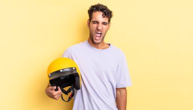 İspanyol yakışıklı adam agresif bir şekilde bağırıyor, çok kızgın görünüyor. Motosiklet kaskı konsepti