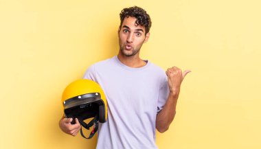 İspanyol yakışıklı adam, inançsızlıktan şaşkın şaşkın bakıyor. Motosiklet kaskı konsepti