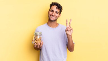 İspanyol yakışıklı adam gülümsüyor ve mutlu görünüyor, zafer ya da barış işareti yapıyor. kurabiye konsepti