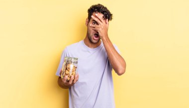 İspanyol yakışıklı adam şok olmuş, korkmuş ya da korkmuş görünüyor. Yüzü elle kapatılmış. kurabiye konsepti