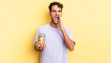 İspanyol yakışıklı adam kendini mutlu hissediyor, elleri ağızının yanında bağırıyor. kurabiye konsepti