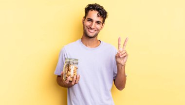 İspanyol yakışıklı adam gülümsüyor ve arkadaş canlısı görünüyor, iki numarayı gösteriyor. kurabiye konsepti