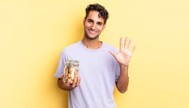 İspanyol yakışıklı adam gülümsüyor ve arkadaş canlısı görünüyor, beş numarayı gösteriyor. kurabiye konsepti