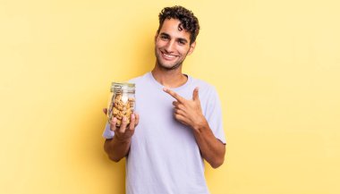 İspanyol yakışıklı adam neşeyle gülümsüyor, mutlu hissediyor ve bir tarafı işaret ediyor. kurabiye konsepti