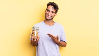 İspanyol yakışıklı adam neşeyle gülümsüyor, mutlu hissediyor ve bir konsept gösteriyor. kurabiye konsepti