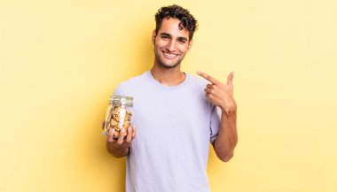 İspanyol yakışıklı adam kendine güvenerek gülüyor ve kendi gülüşüne işaret ediyor. kurabiye konsepti