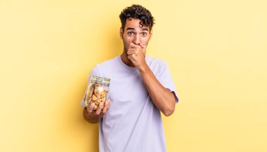 İspanyol yakışıklı adam şok olmuş bir şekilde ağzını kapatıyor. kurabiye konsepti