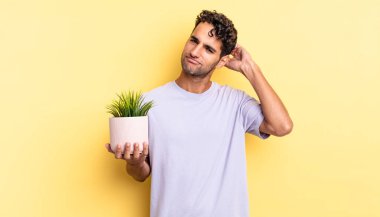 İspanyol yakışıklı adam mutlu bir şekilde gülümsüyor ve hayal kuruyor ya da şüphe ediyor. dekoratif bitki konsepti