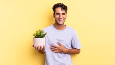 İspanyol yakışıklı bir adam komik bir şakaya yüksek sesle gülüyor. dekoratif bitki konsepti