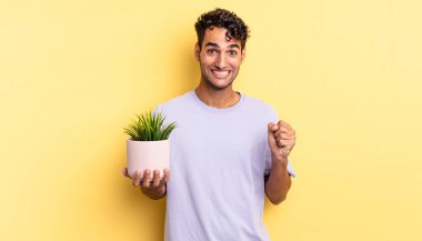 İspanyol yakışıklı adam şokta, gülüyor ve başarıyı kutluyor. dekoratif bitki konsepti