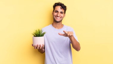 İspanyol yakışıklı adam kamerayı göstererek seni seçiyor. dekoratif bitki konsepti