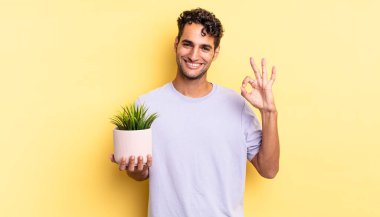İspanyol yakışıklı adam kendini mutlu hissediyor, iyi bir jestle onaylıyor. dekoratif bitki konsepti