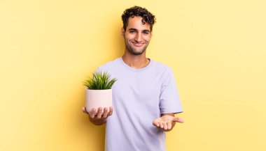 İspanyol yakışıklı adam mutlu bir şekilde gülümsüyor ve bir konsept sunuyor. dekoratif bitki konsepti