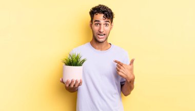 İspanyol yakışıklı adam mutlu hissediyor ve heyecanla kendini işaret ediyor. dekoratif bitki konsepti