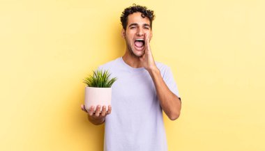 İspanyol yakışıklı adam kendini mutlu hissediyor, elleri ağızının yanında bağırıyor. dekoratif bitki konsepti