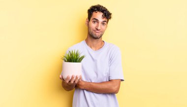 İspanyol yakışıklı adam omuz silkiyor, kafası karışık ve kararsız. dekoratif bitki konsepti