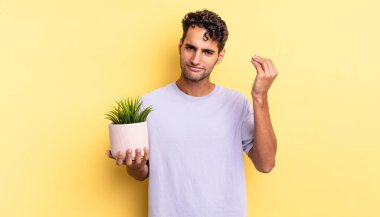 İspanyol yakışıklı adam kapiş ya da para hareketi yapıyor, sana ödemeni söylüyor. dekoratif bitki konsepti