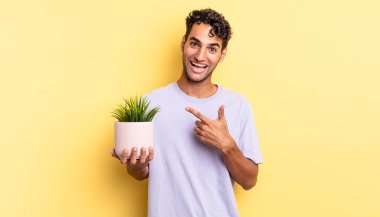 İspanyol yakışıklı adam heyecanlı ve şaşırmış görünüyor. dekoratif bitki konsepti