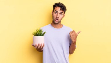 İspanyol yakışıklı adam, inançsızlıktan şaşkın şaşkın bakıyor. dekoratif bitki konsepti