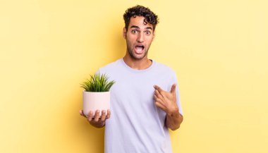 İspanyol yakışıklı adam şok olmuş ve ağzı açık, kendini işaret ederek şaşırmış görünüyor. dekoratif bitki konsepti
