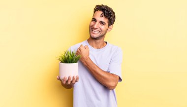 İspanyol yakışıklı adam kendini mutlu hissediyor ve bir meydan okumayla yüzleşiyor ya da kutluyor. dekoratif bitki konsepti