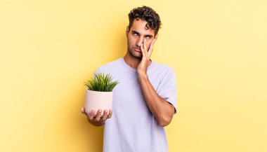 İspanyol yakışıklı bir adam yorgun, bıkkın ve uykulu hissediyor. dekoratif bitki konsepti