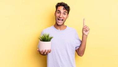 İspanyol yakışıklı bir adam bir fikri fark ettikten sonra mutlu ve heyecanlı bir dahi gibi hissediyor. dekoratif bitki konsepti