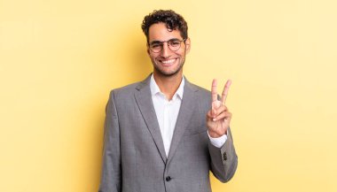 İspanyol yakışıklı adam gülümsüyor ve arkadaş canlısı görünüyor, iki numarayı gösteriyor. iş kavramı