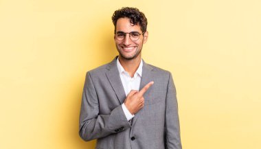 İspanyol yakışıklı adam neşeyle gülümsüyor, mutlu hissediyor ve bir tarafı işaret ediyor. iş kavramı