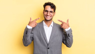 İspanyol yakışıklı adam kendine güvenerek gülüyor ve kendi gülüşüne işaret ediyor. iş kavramı