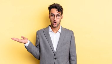 İspanyol yakışıklı adam şaşırmış ve şok olmuş görünüyor. Çenesi düşmüş ve elinde bir nesne var. iş kavramı