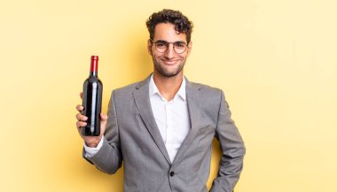 İspanyol yakışıklı adam mutlu bir şekilde gülümsüyor, eli kalçasında ve kendinden emin. şarap şişesi konsepti
