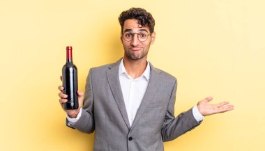 İspanyol yakışıklı adam şaşkın, şaşkın ve şüpheci hissediyor. şarap şişesi konsepti