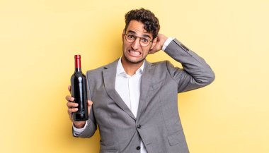 İspanyol yakışıklı adam kendini stresli, endişeli ya da korkmuş hissediyor, elleri başının üstünde. şarap şişesi konsepti