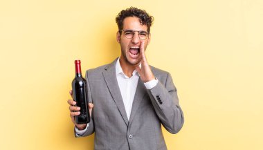 İspanyol yakışıklı adam kendini mutlu hissediyor, elleri ağızının yanında bağırıyor. şarap şişesi konsepti