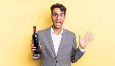İspanyol yakışıklı adam kendini mutlu hissediyor ve inanılmaz bir şeye hayret ediyor. şarap şişesi konsepti