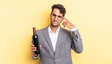 İspanyol yakışıklı adam kafası karışık ve şaşkın hissediyor, senin deli olduğunu gösteriyor. şarap şişesi konsepti