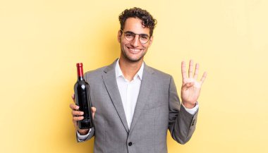 İspanyol yakışıklı adam gülümsüyor ve arkadaş canlısı görünüyor, dört numarayı gösteriyor. şarap şişesi konsepti
