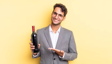 İspanyol yakışıklı adam neşeyle gülümsüyor, mutlu hissediyor ve bir konsept gösteriyor. şarap şişesi konsepti