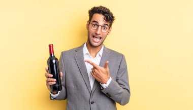 İspanyol yakışıklı adam heyecanlı ve şaşırmış görünüyor. şarap şişesi konsepti