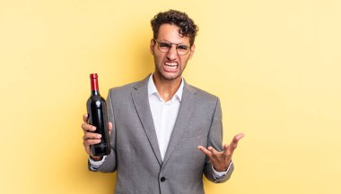 İspanyol yakışıklı adam sinirli, sinirli ve sinirli görünüyor. şarap şişesi konsepti