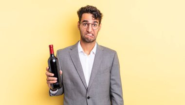 İspanyol yakışıklı adam kafası karışmış ve şaşkın görünüyor. şarap şişesi konsepti