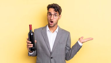 İspanyol yakışıklı adam şaşırmış ve şok olmuş görünüyor. Çenesi düşmüş ve elinde bir nesne var. şarap şişesi konsepti