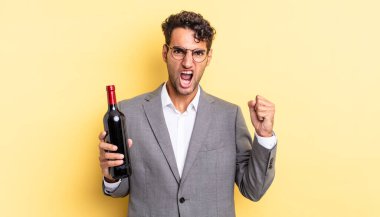 İspanyol yakışıklı adam sinirli bir ifadeyle agresif bir şekilde bağırıyor. şarap şişesi konsepti