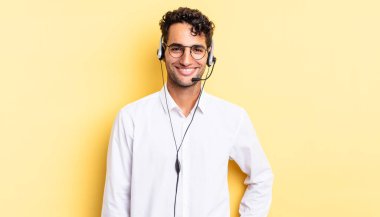 İspanyol yakışıklı adam mutlu bir şekilde gülümsüyor, eli kalçasında ve kendinden emin. tele pazarlamacı konsepti