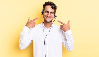 İspanyol yakışıklı adam kendine güvenerek gülüyor ve kendi gülüşüne işaret ediyor. tele pazarlamacı konsepti